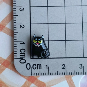 Miniature black resin cartoon cat charm shown on measuring mat for precise size detail