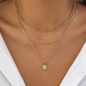 Close-up of layered gold necklace with rhinestone pendant and classic link chains on model