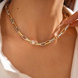Detail of two-tone gold and silver interlocking geometric chain necklace on a model