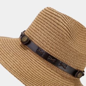 Detail of woven straw sun hat featuring brown leather band and antique sun-patterned button