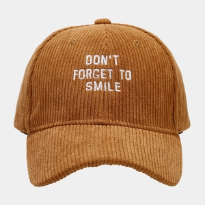 Close-up of white embroidery text on brown corduroy baseball cap with fine texture