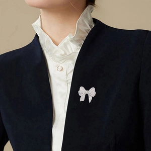 Elegant silver bow brooch with sparkling zircon inlays pinned on a dark suit lapel