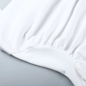 Detailed close-up of smocked waist stitching on the white A-line summer dress
