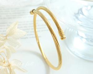 Detail view of a gold twisted cable open cuff bracelet with minimalist texture design