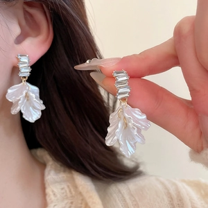 Dettaglio degli orecchini a fiore con perle, cristalli e petali color oro