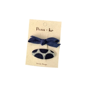 Navy blue fabric bow and embroidered oval hair clip set on display card