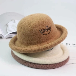 Close-up of stacked wool hats in caramel, beige, and pink with Smile embroidery