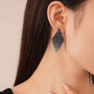 Close-up of geometric diamond-encrusted rhombic stud earrings worn by a model