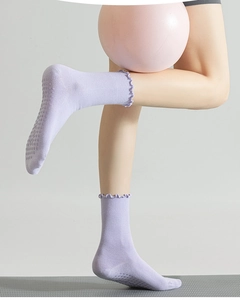 Detail view of purple non-slip yoga socks featuring frilled cuffs on a yoga ball