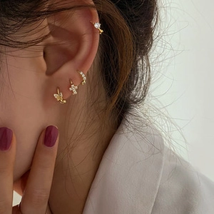 Detail of gold butterfly charms and zircon ear cuffs worn on model ear