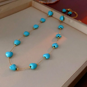 Bohemian turquoise heart necklace with gold beads on a gold chain in a jewelry tray