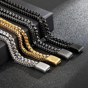Detail of square-link Cuban bracelets in black, gold, and silver stainless steel finishes
