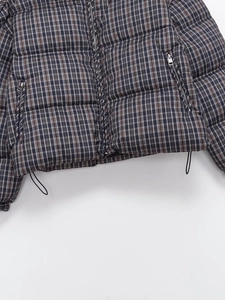 Detail of checkered puffer jacket hem with adjustable drawstring and zip pockets