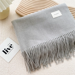 Detail of grey fringed scarf showing soft texture and woven label with Self Service text