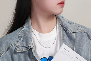 Minimalist silver snake chain necklace worn by a model in casual white outfit