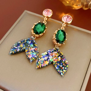 Gros plan de boucles d'oreilles queue de sirène colorées avec paillettes et cristaux