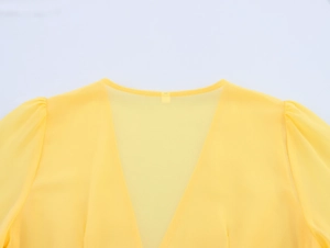 Detailed macro view of yellow V-neckline with delicate puff sleeves and lace stitching