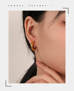 Close-up of chunky gold hoop earrings worn by a model showcasing the polished metal finish