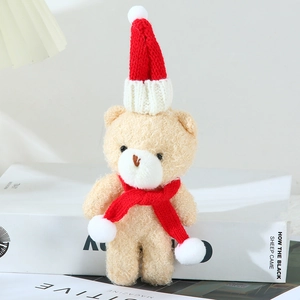 Detail of a beige plush teddy bear wearing a festive red knitted Christmas hat and scarf