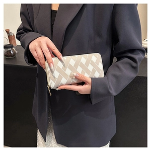 Close-up of woman holding a white and beige cross pattern long wallet with gold zipper