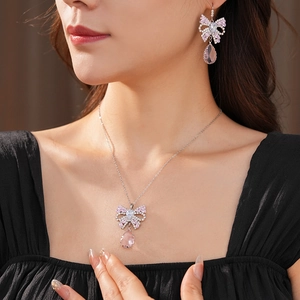 Close-up of pink crystal bow necklace and teardrop earrings set on female model