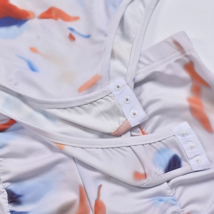 Macro shot of white snap buttons and reinforced stitching on tie-dye bodysuit bottom