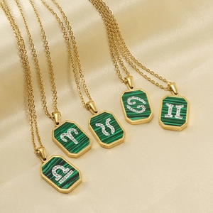 Gros plan de pendentifs zodiaque en malachite posés sur un tissu élégant en soie champagne