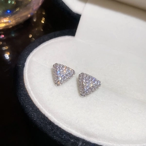 Gros plan de boucles d'oreilles triangles argentées avec zircons dans un écrin à bijoux