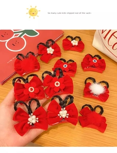 Detailed flat lay of red velvet hair bows with pearls, pom-poms and braided hair extensions