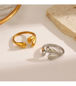 Close-up of gold and silver water drop open rings on a minimalist stone background