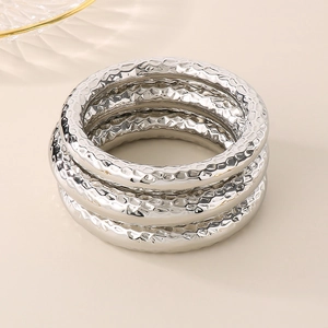 Detailed view of three silver textured stainless steel bangles with a hammered finish surface