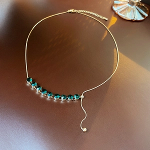Dettaglio collana placcata oro con zirconi color smeraldo e catena a serpente sottile