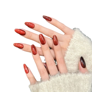 Cat eye press-on nails in deep red-brown almond shape with glitter and rhinestone accents