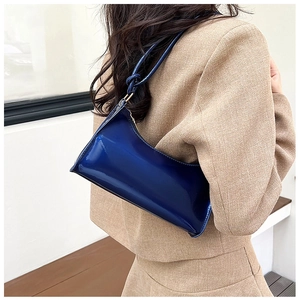 Blue glossy patent leather hobo bag with knot detail shown on model in khaki suit