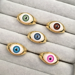 Detailed macro view of gold evil eye resin rings in various iris colors on a jewelry tray