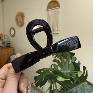 Große schwarze glänzende Haarklammer mit Schleifen-Design in der Hand gehalten