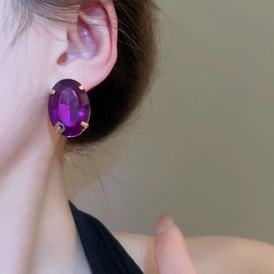 Close-up of vintage gold-plated oval earrings with large purple faceted gemstones