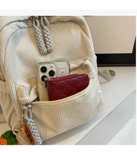 Detail view of corduroy backpack front zipper pocket with phone and wallet inside