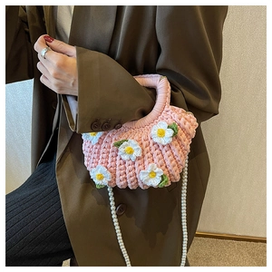 Detailed view of pink crochet daisy bag with pearl strap worn with a brown blazer