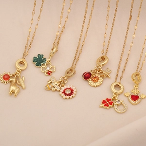 Close-up of gold-plated necklaces with enamel clover, bee, and heart-shaped pendants