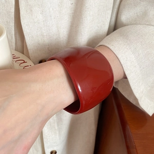 Close-up of a wide irregular resin bangle in bold red finish on a fashion model