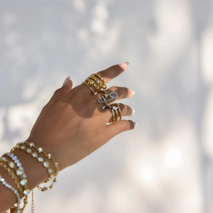 Nahaufnahme von mehrlagigen Goldperlenringen und Sicherheitsnadel-Ring mit Armbändern