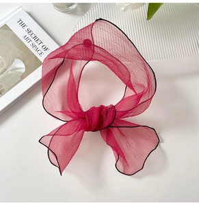 Close-up of rose red organza scarf with fine black stitching and translucent texture