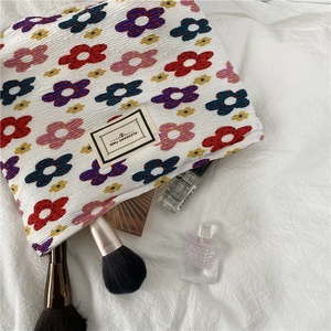 Close-up of floral seersucker cosmetic bag with Pleasant Time label and makeup tools