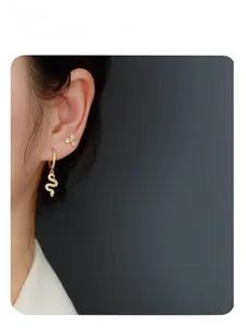 Close-up of model wearing gold snake drop earrings with sparkling zircon crystals