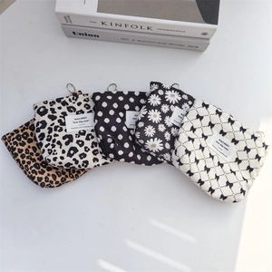 Vintage corduroy makeup bags with animal and floral prints on a minimalist white desk