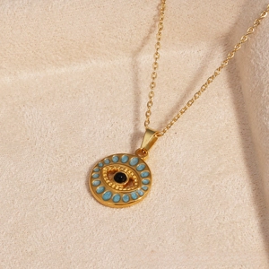 Detailed view of evil eye pendant with blue enamel trim and gold link chain on velvet