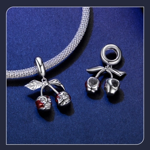 Macro detail of S925 sterling silver cherry skull charms with red enamel accents