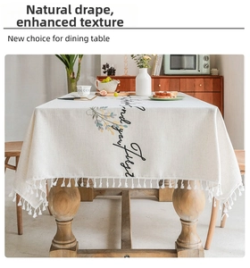 Detail of beige cotton linen tablecloth with tassel edges and elegant green leaf print