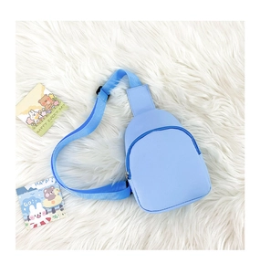 Close-up of light blue kids crossbody bag with adjustable nylon strap on plush background